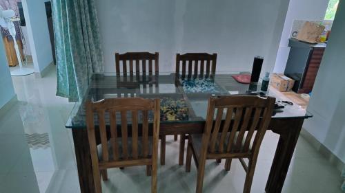 a dining room table with four chairs and a glass top at Kochuparampil House in Idukki
