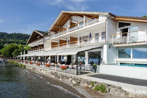 a building next to a body of water at Strandhotel Seeblick in Faulensee