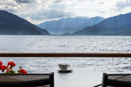 a cup of coffee sitting on a table by the water at Strandhotel Seeblick in Faulensee