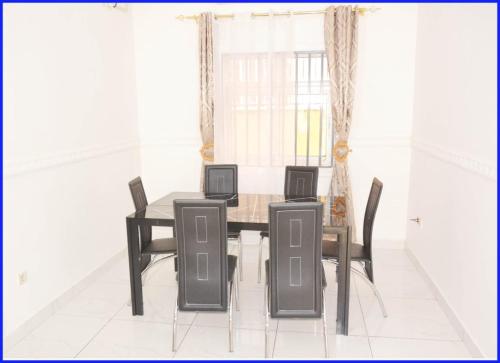 a dining room with a table and four chairs at Appartement New Stading YAOUNDE - MIMBOMAN MAETURE in Yaoundé