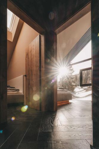 a room with a large sliding door with the sun shining through at Hüttendorf Schlögelberger in Sankt Margarethen im Lungau