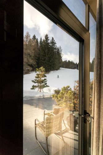 a sliding glass door with a chair on a porch at Hüttendorf Schlögelberger in Sankt Margarethen im Lungau