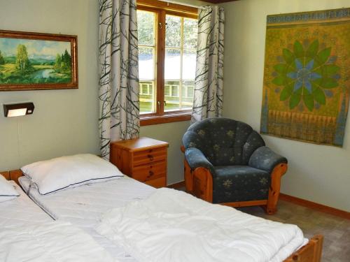 um quarto com uma cama, uma cadeira e uma janela em Holiday home Oldedalen em Briksdalsbre