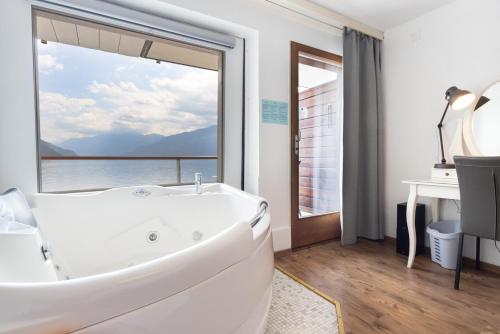 uma casa de banho com banheira e uma grande janela em Strandhotel Seeblick em Faulensee