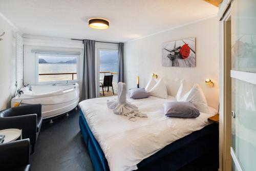 a bedroom with a large bed and a bath tub at Strandhotel Seeblick in Faulensee
