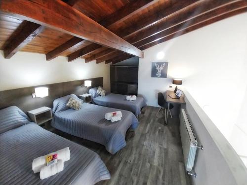 a bedroom with two beds and a desk in it at Las Victorias Suites Bariloche in San Carlos de Bariloche