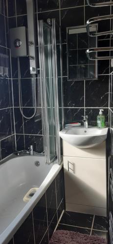 a black tiled bathroom with a sink and a tub at Our Guests Are Royal (EL) Wellingborough in Wellingborough