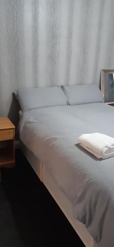 a bed with white sheets and a wooden night stand at Our Guests Are Royal (EL) Wellingborough in Wellingborough