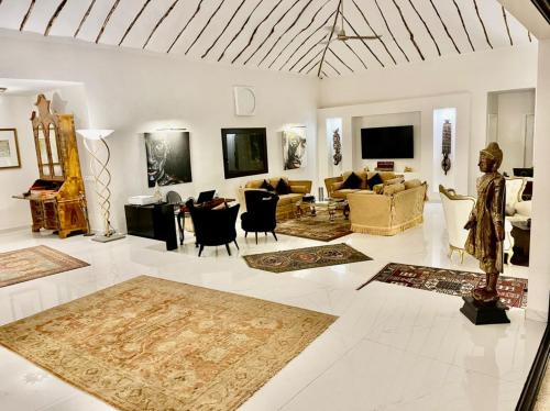 een woonkamer met banken en stoelen en een televisie bij Villa Le Petit Paradis Saly Boutique Hotel in Ngaparou