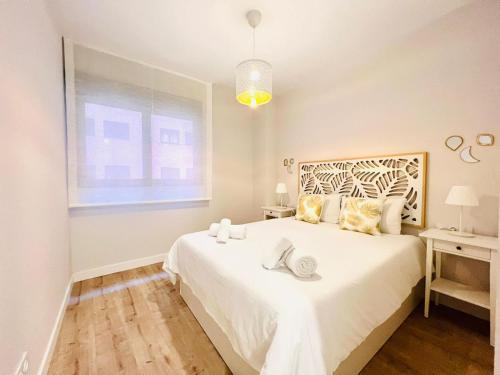a white bedroom with a large bed and a window at Sky Garden & seasonal pool views by ELE Apartments in Málaga