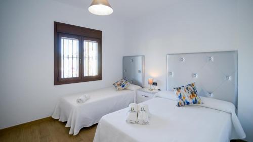 Cette chambre blanche dispose de deux lits et d'une fenêtre. dans l'établissement Casa Rural Tajo de Gómer Riogordo by Ruralidays, à Ríogordo