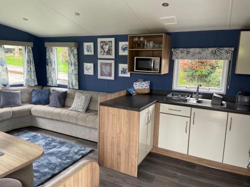 eine Wohnwagen-Küche und ein Wohnzimmer mit einem Sofa und einem Tisch in der Unterkunft Newquay Bay Resort - Sea Breeze 61 in Newquay
