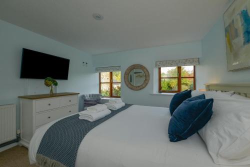 a bedroom with a large white bed and a television at Lily Cottage in Looe