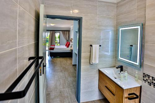 a bathroom with a sink and a mirror and a bed at JMK at 49 LaPirogue - Families only in Ballito