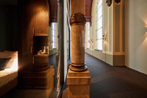 a column in a room with a bed and windows at Heavens Hotel in Hoorn