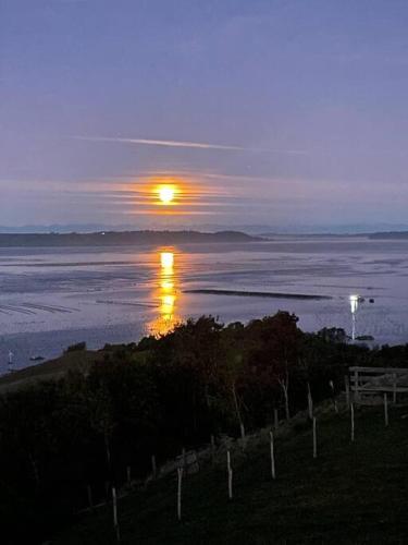 a sunset over a body of water with a fence at Bella casa de campo con panorámica vista al mar in Dalcahue