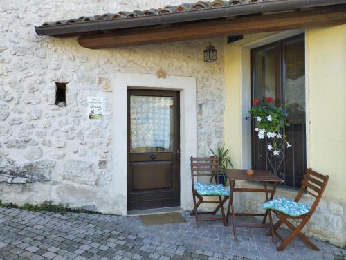 a house with two chairs and a table in front of a door at Alloggio Agrituristico Abruzzomio - Casa Somarello in Goriano Valli
