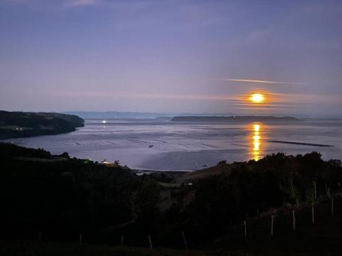 a view of a river with the sun in the distance at Bella casa de campo con panorámica vista al mar in Dalcahue