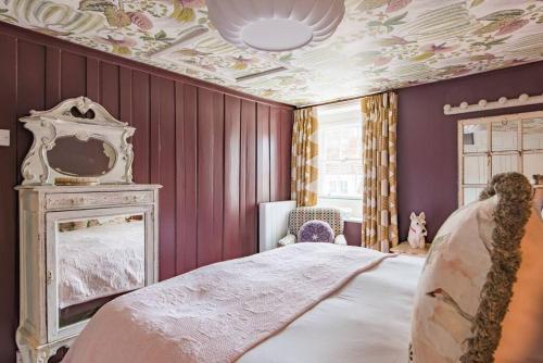 a bedroom with purple walls and a bed with a mirror at Noggin in Deal