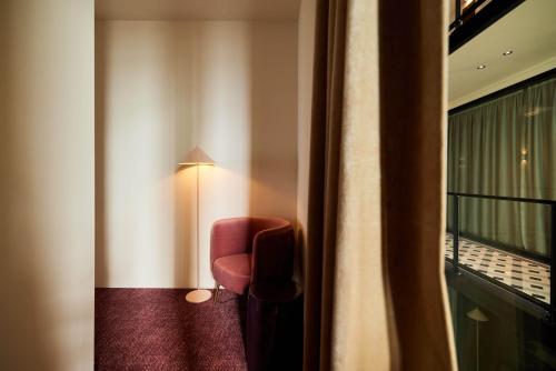 a red chair in a room with a window at Heavens Hotel in Hoorn