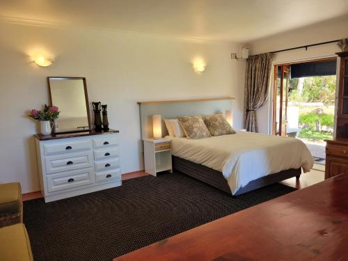 een slaapkamer met een bed met een spiegel en een dressoir bij Froggy Farm Self Catering in Simonʼs Town