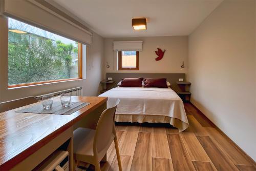 1 dormitorio con cama, mesa y ventana en APARTS LA FARFALLA en El Chalten