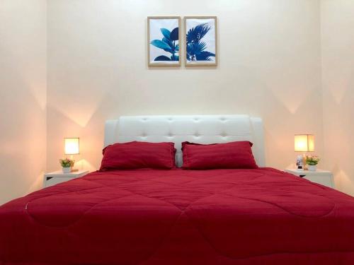 a bedroom with a red bed with two lamps at RumahKu Homestay, Taman Jasin Perdana in Jasin