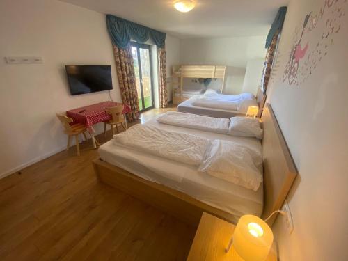 a bedroom with two beds and a table and a desk at Laimerhof in Rifiano