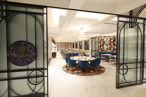 a restaurant with blue chairs and tables and glass walls at Radisson Mumbai Goregaon in Mumbai