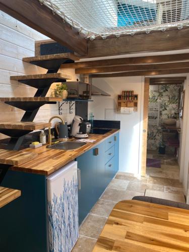 a kitchen with blue cabinets and a wooden ceiling at La Tiny Blue - maison insolite pour 2 - sans Tv in Saint-Aignan