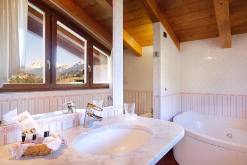 La salle de bains est pourvue d'un lavabo, de toilettes et de fenêtres. dans l'établissement Park Hotel Leonardo, à Moena