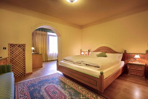 a bedroom with a bed and a table and a rug at Park Hotel Leonardo in Moena