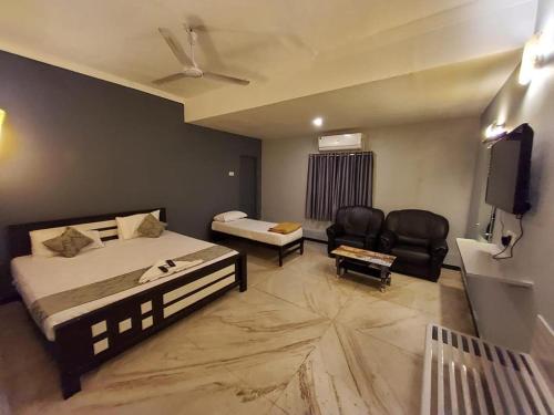 1 dormitorio con 1 cama, TV y sillas en Le Grace Annasalai en Chennai