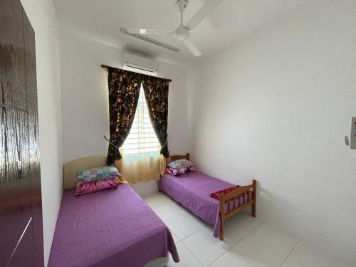 2 camas en una habitación con sábanas moradas y una ventana en Family Holiday Home With Wifi & Netflix en Sungai Petani