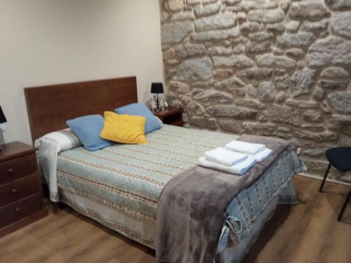 a bedroom with a bed with blue and yellow pillows at Casa da Eira in Lobios
