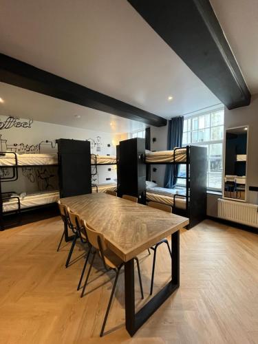 a room with a table and chairs and bunk beds at Heart of Amsterdam Hostel in Amsterdam