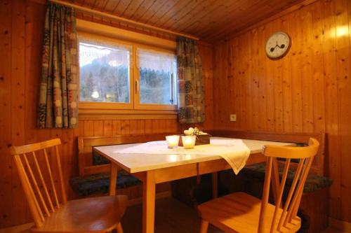 ein Esszimmer mit einem Tisch, Stühlen und einer Uhr in der Unterkunft Haus Dekker in Mellau