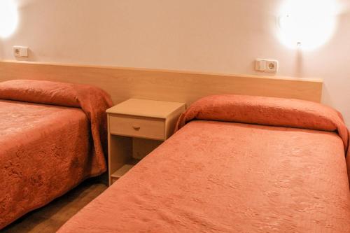 a hotel room with two beds and a night stand at Hotel Saloria in Alins