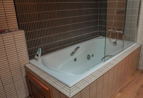 uma banheira numa casa de banho em azulejo com um chuveiro em Hotel Saloria em Alins