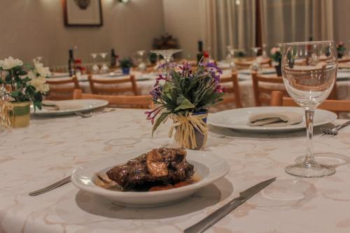 a table with a plate of meat and a glass of wine at Hotel Saloria in Alins