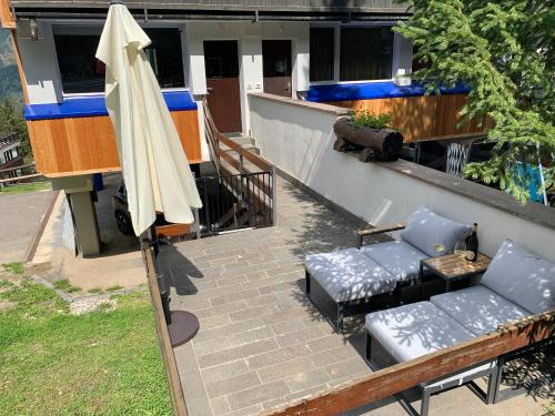 a patio with an umbrella and two chairs and a couch and a table at Casa Lorica Marilleva 1400 in Marilleva