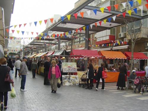 a group of people walking around a market with flags at Mizpe Yam Boutique Hotel in Netanya