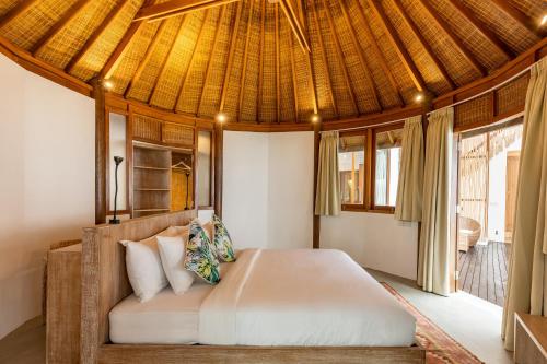 a bedroom with a bed with a thatched roof at The Lagoon Canggu in Canggu