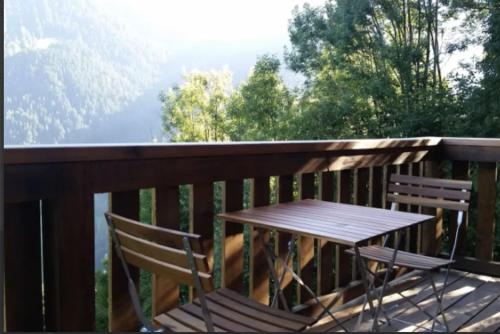 a wooden table and chairs on a deck with a view at Heidi Chalet in Rossinière