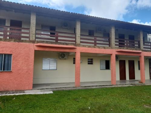 um edifício vermelho e branco com um relvado em Pousada Éden Rio em Ilhéus