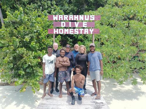 a group of people posing for a picture under a sign at Warahnus dive homestay in Kri