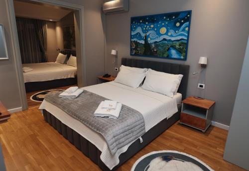 a bedroom with two beds and a painting on the wall at Vila Mariss in Korçë