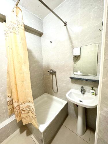 a bathroom with a tub and a sink and a shower curtain at Evita Apartment in Bishkek