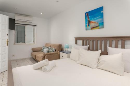 a bedroom with a large white bed and a couch at Casa Julia in Playa de las Americas