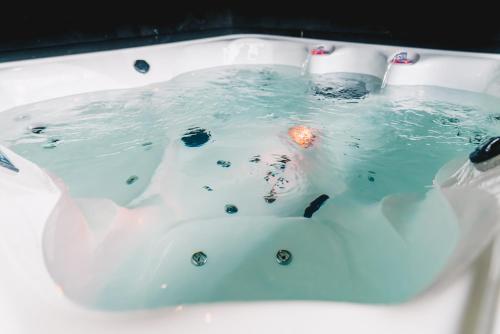 a bathtub filled with water with a bottle in it at Wellness Bed & Breakfast by Leef in Maasland